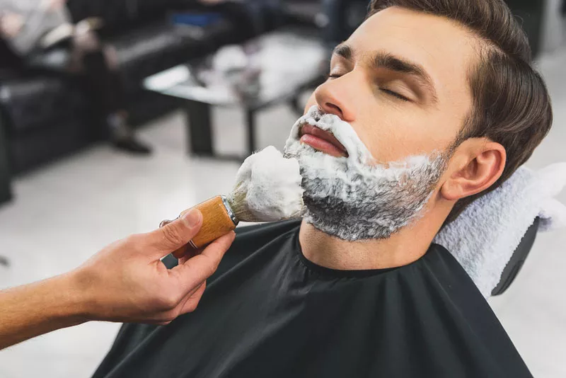 Barbero cortando la barba paso a paso a cliente