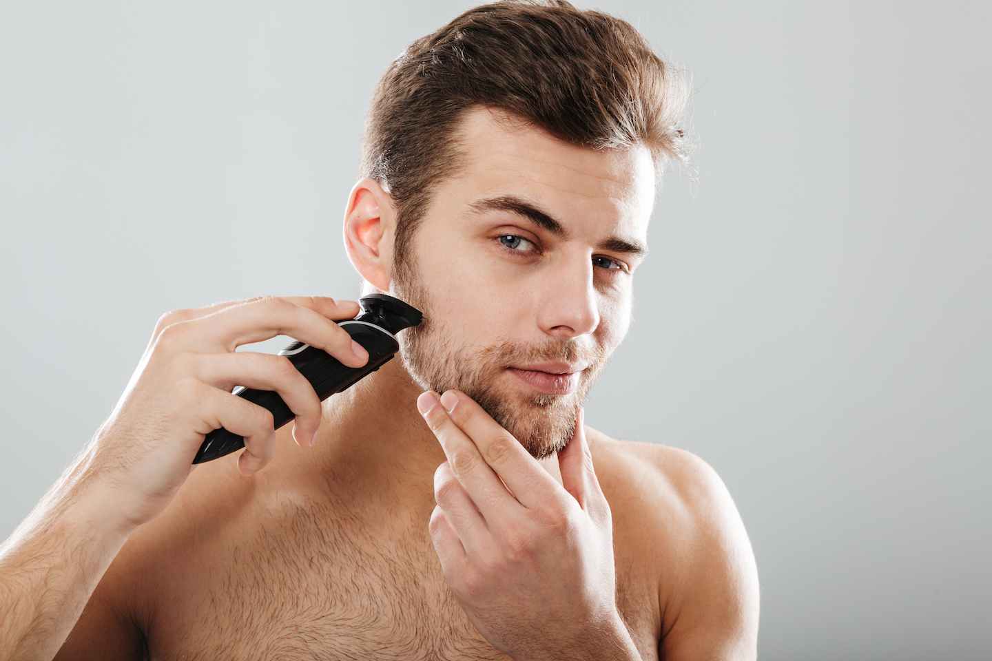 man trimming his beard at home